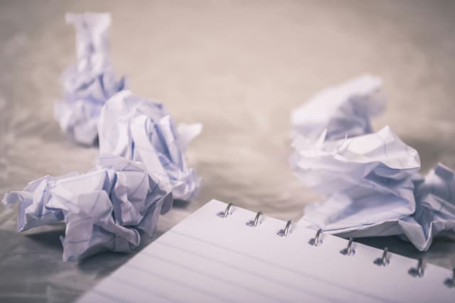 Crumpled balls of paper next to a notebook.